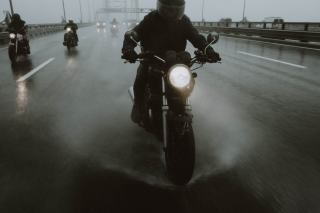 Motard en veste de pluie sur une route mouillée